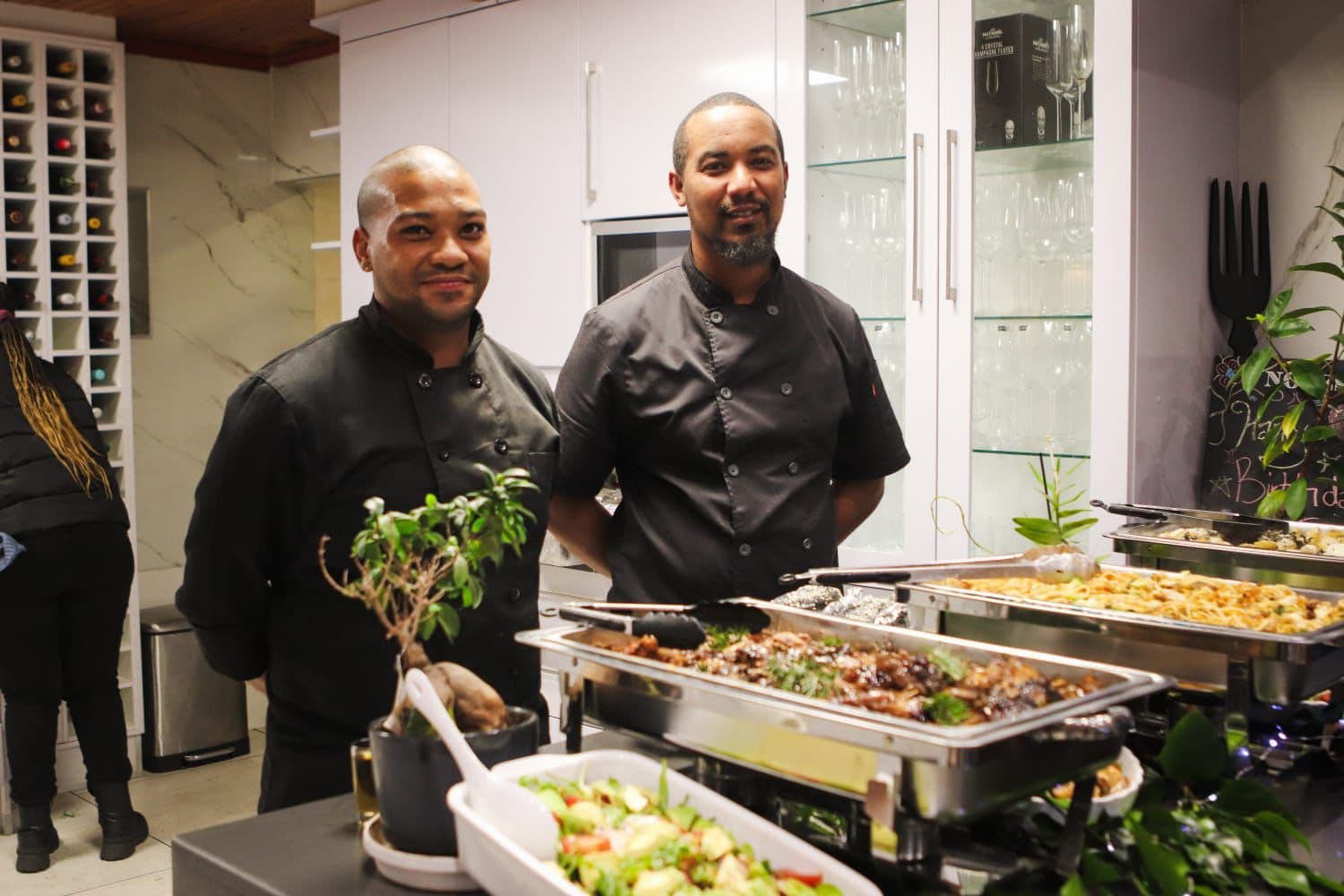 Two Why Not?! Catering chefs standing behind a buffet of plated food